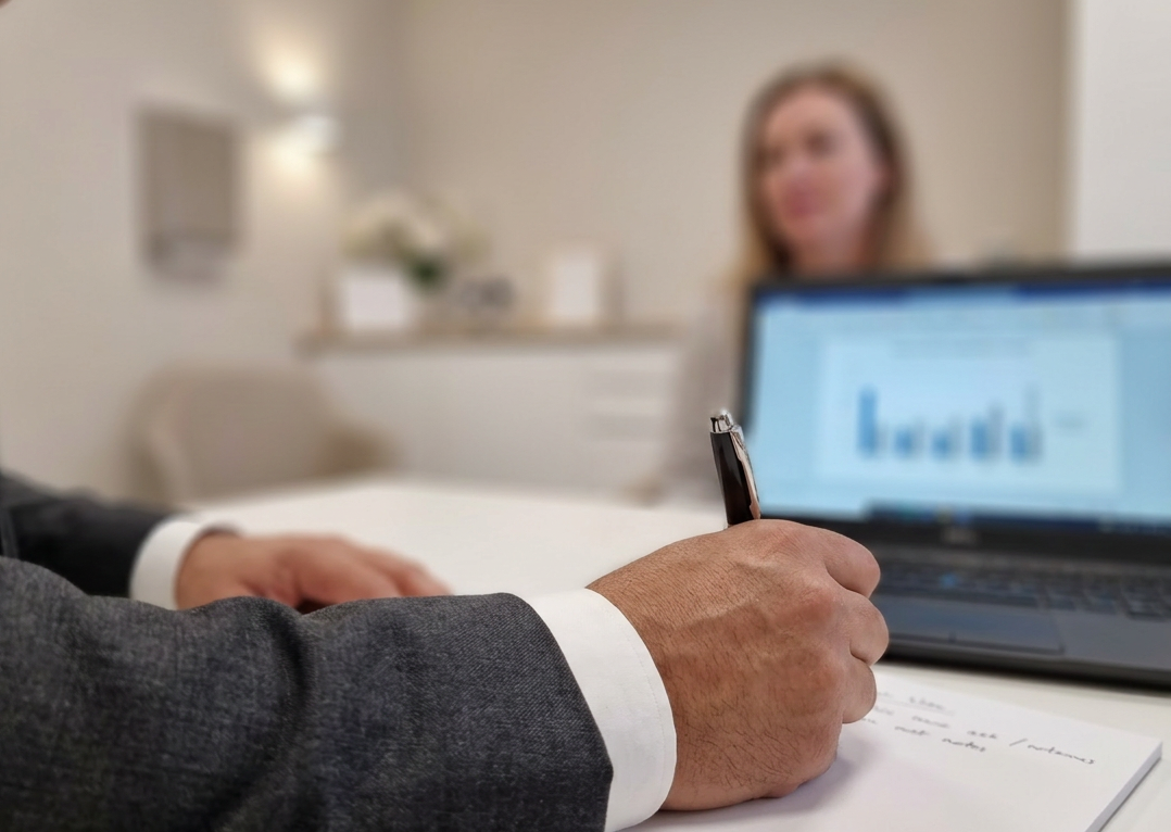 Consultation desk with surgeon writing notes during a private clinic appointment.